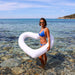 woman in blue swimsuit standing in shallow water with white heart float around her waist