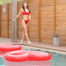 woman in red swimsuit posing by a fence next to a red heart shaped float from the best pool float brand