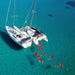 Ariel photo of a group of people in the sea, in lôteli red heart shaped floats off two boats in clear blue water