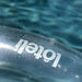 Close up photo of silver loteli logo and double valve on clear ring pool float
