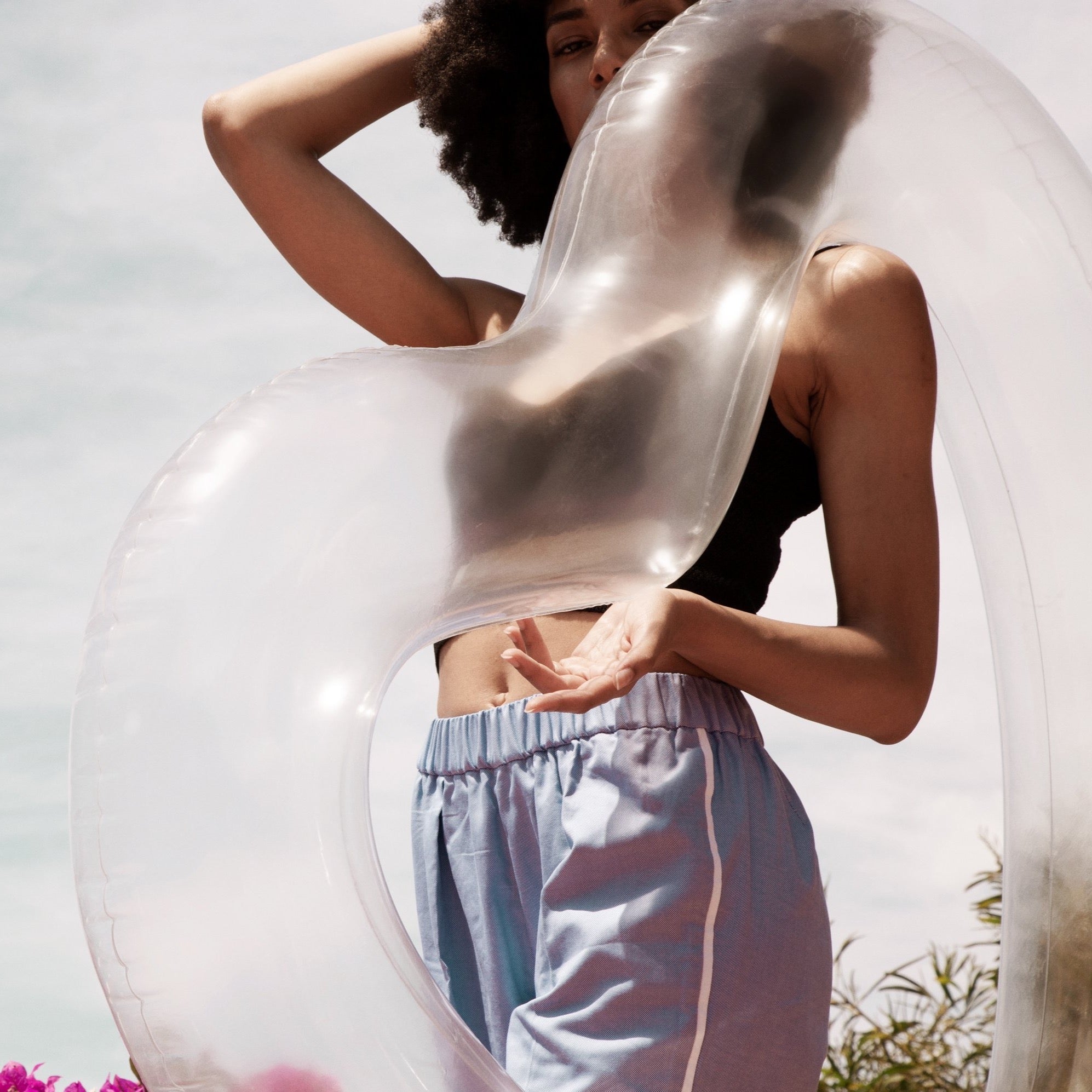 Stylish woman holding her clear heart float over her shoulder, looking down into the camera, facing left. 